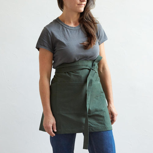 Our pure cotton half apron is both stylish and utilitarian, and designed to fit most body types. Featuring wide side and front pockets, it is ideal for working in the garden, kitchen, or studio. Each apron is soft-washed for added comfort. Azo-free dye.  Dimensions: 17” W x 25” H with elongated waist ties
