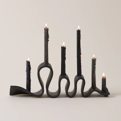 Black candle holder with five candles on a light gray background