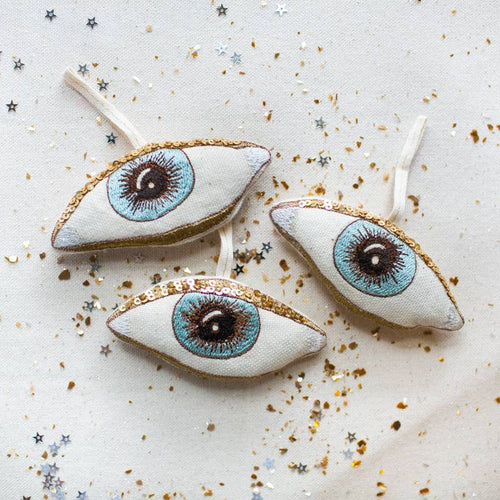 Decorative eye-shaped ornaments with gold accents on a light background
