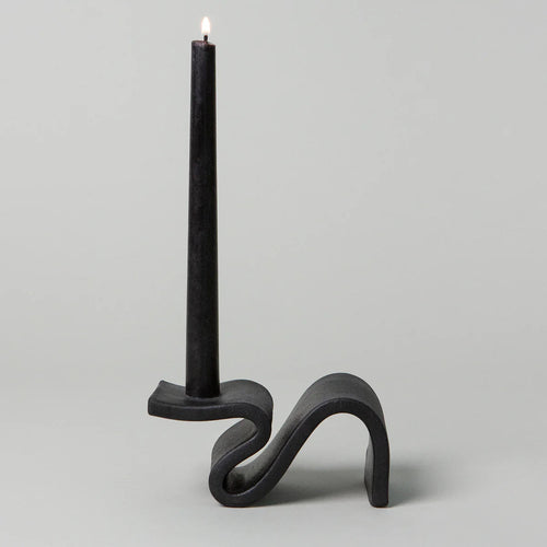 Black candle holder with a lit candle on a light gray background