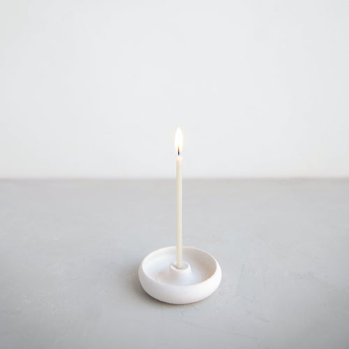 Floral Society white wishing candle lit in a small ceramic candle holder. Skinny taper candle can be used as a meditation candle or birthday candle alike