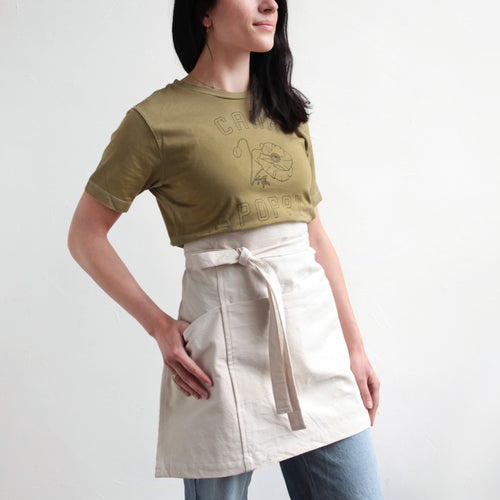 Person wearing a green floral shirt and half apron in canvas by the floral society.