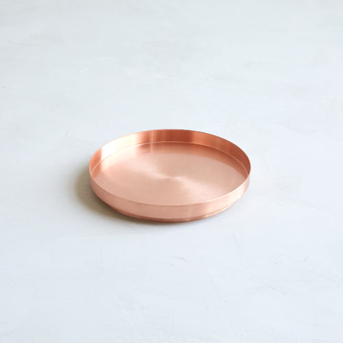 This copper pillar plate is the perfect companion to our fancy pillar candles. Its wide base provides a safe surface to burn pillar candles and the simplistic design proves to be an ideal accent piece to any space. Makes a great jewelry catchall too. Made of copper-plated iron and hand-finished—slight variations may occur.